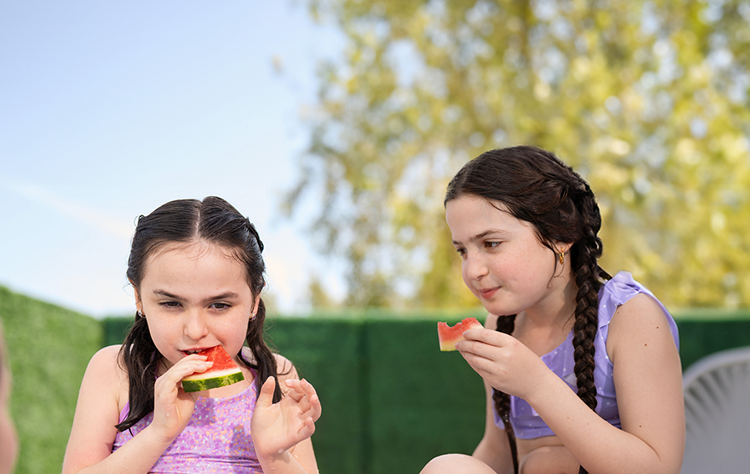 Clare, living with Rett syndrome, eating watermelon with her sister